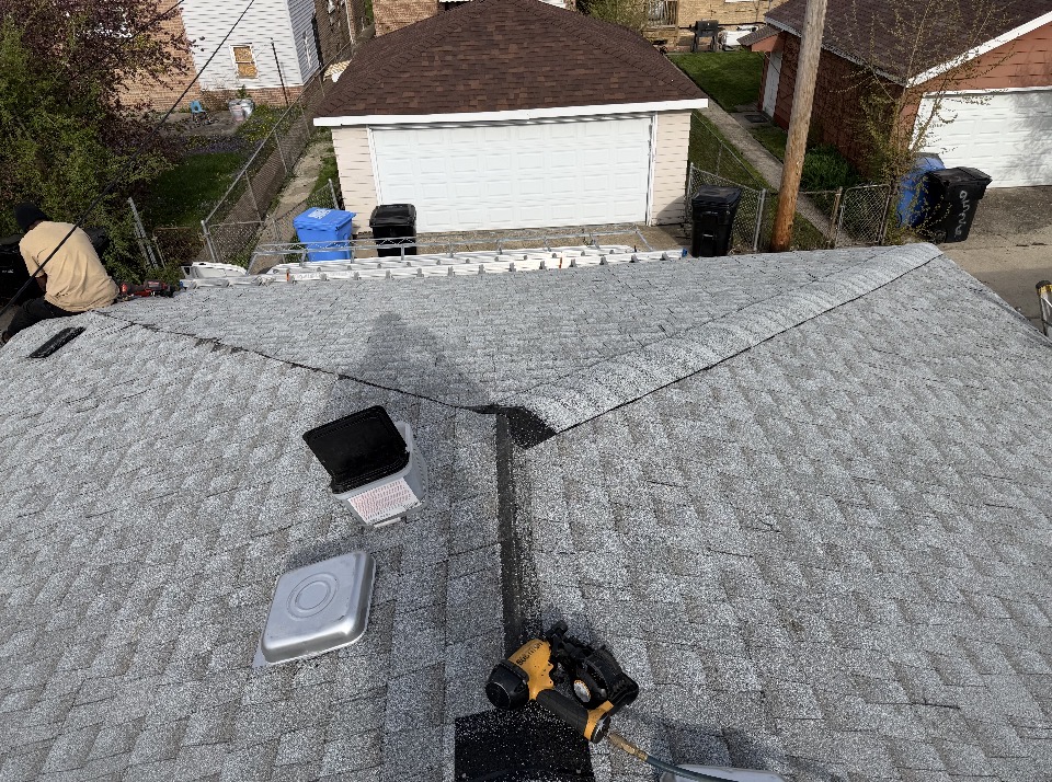 Finished gray shingle roof with vents and tools on the job site
