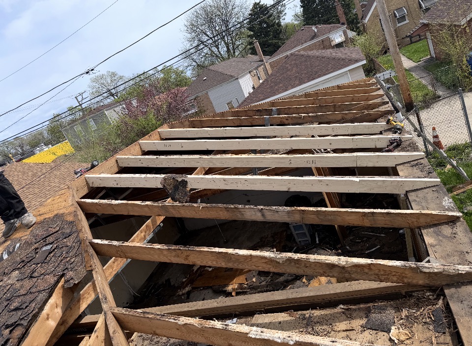 Roof framing exposed during a complete tear-off in a residential neighborhood